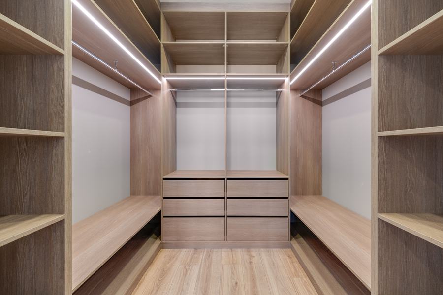 Dressing en bois clair éclairé par des bandes de LED, avec étagères et tiroirs