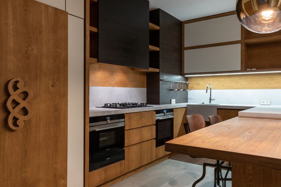 Cuisine contemporaine en bois, avec plan de travail clair, plaque de cuisson et four encastré